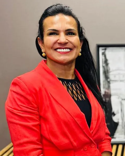 Dra. Ivone Duque, sorrindo, de blazer vermelho